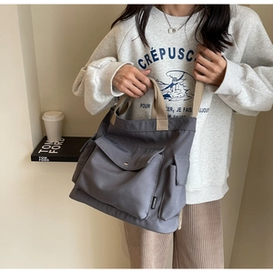 Detail of grey canvas tote bag with front buckle pocket and adjustable beige shoulder strap