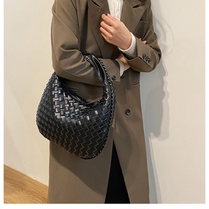 Close-up of black woven leather texture on a crescent shoulder bag for women