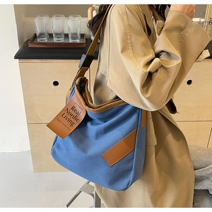 Detail of blue canvas tote bag featuring brown leather trim and Nordic logo label