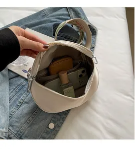 Détails de l'intérieur d'un sac bandoulière beige avec bandoulière brodée et accessoires