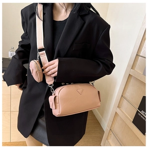 Detail of pink pebbled leather crossbody bag with fabric strap and mini pouch charm