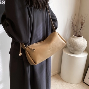 2024 minimalist khaki cylinder PU leather crossbody shoulder bag worn by a model