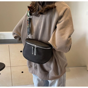 Détail du sac bandoulière en nylon noir avec doubles zips argentés et bandoulière colorée
