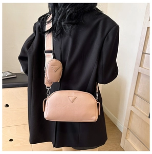 Detail of nude pink pebbled leather crossbody bag with round coin purse on wide strap