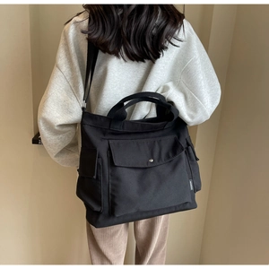 Detail view of durable black canvas tote bag with multiple pockets and fashion label