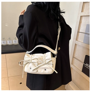 Detail showing creamy white PU leather shoulder bag with ruffled opening and bow accents