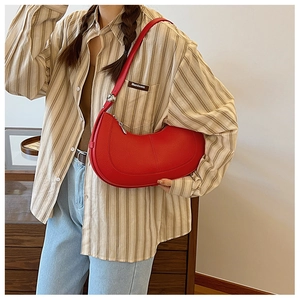 Detail of red crescent shoulder bag in lychee pattern leather with a silver ball metal charm