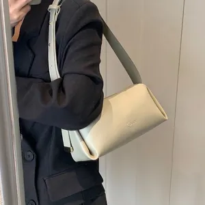 LUKADI beige PU leather baguette bag worn as a shoulder bag in a modern indoor setting