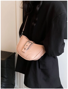 Détail du sac bandoulière rose clair en similicuir verni avec boucle argentée sur blazer