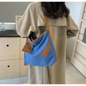 Detail of Nordic blue canvas crossbody bag with brown leather strap worn by a model