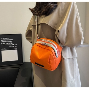 Dettaglio della borsa a tracolla in nylon arancione con cinturino ricamato a fiori colorati