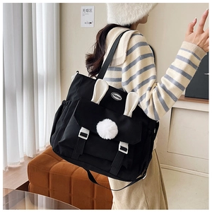 Detail of black nylon tote with rabbit ears and plush ball on the front flap