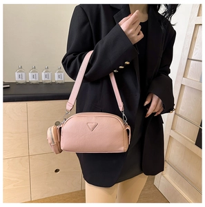 Close-up of pink PU leather crossbody bag with triangular metal plate and mini round purse