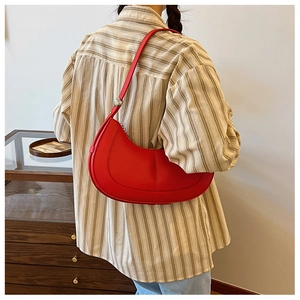 Detail view of the red crescent shoulder bag with a distinct lychee leather texture and strap