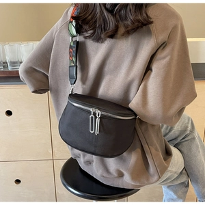 Détail du sac bandoulière noir en demi-lune avec large sangle à motifs floraux colorés