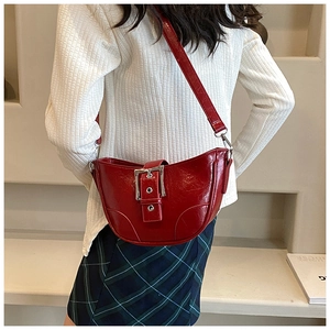 Détail du sac bandoulière rouge en forme de croissant avec boucle métallique argentée sur cuir