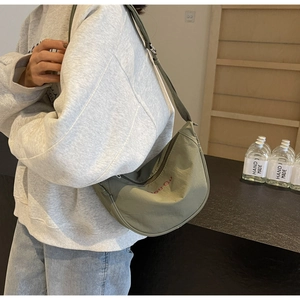 Détail du sac demi-lune en nylon vert avocat avec lettrage brodé rouge élégant