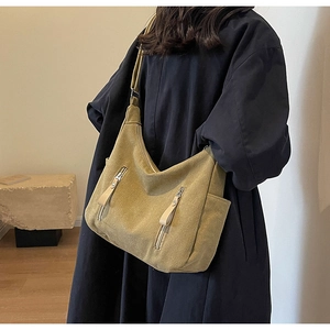 Detailed side view of khaki canvas hobo bag featuring decorative vertical zippers