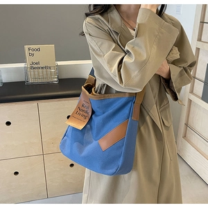 Detail of blue canvas tote bag with brown leather trim and Nordic living tag
