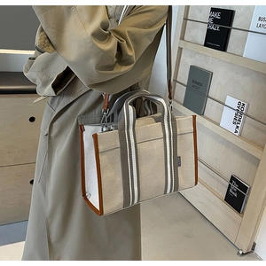 Detail of canvas tote bag showing thick off-white fabric with brown leather trim details