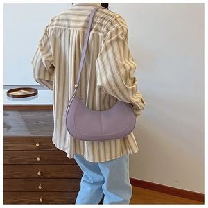 Close-up of lilac purple semi-circle hobo bag worn by a model in a cozy indoor setting