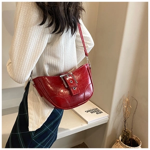 Détail du sac en cuir verni rouge avec boucle métallique polie et bandoulière élégante