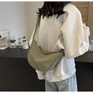 Sac bandoulière demi-lune vert olive en nylon avec broderie porté par un mannequin