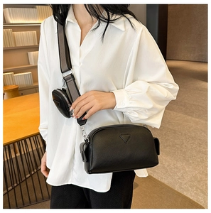 Detail of minimalist black crossbody bag with detachable coin purse and metal logo