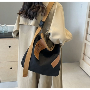 Detail of black canvas crossbody bag with brown wide strap and Nordic living leather patch