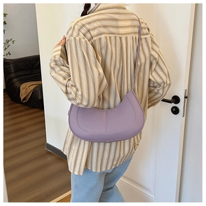 Close-up of lavender crescent shoulder bag with lychee texture on a model's back