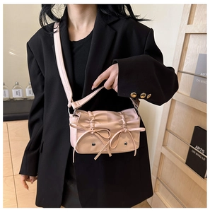 Detail of pink PU leather handbag featuring decorative bows and pleated flap design