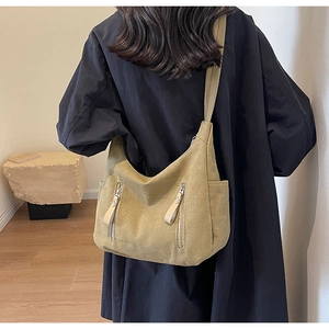 Detail of a khaki canvas hobo bag with dual vertical zipper pockets on a female model