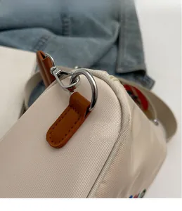 Détail du crochet en métal argenté et du connecteur en cuir marron du sac oxford