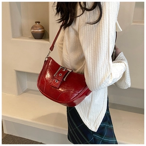 Détail d'un sac hobo en cuir verni rouge avec boucle argentée et bandoulière réglable