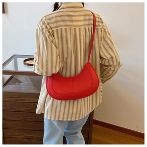 Detail of red pebbled leather hobo shoulder bag with stitching on striped shirt backdrop