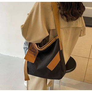 Detail of minimalist canvas crossbody bag with wide brown strap worn by a model