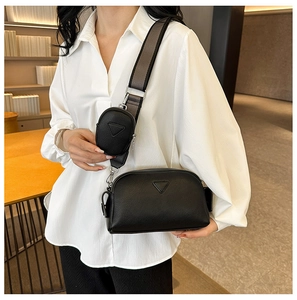 Detail of a black pebbled PU leather crossbody bag with a detachable coin purse on the strap