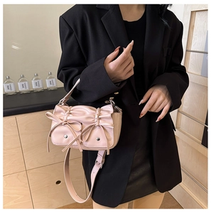 Pink PU crossbody bag featuring pleated bow design shown on a stylish model's outfit