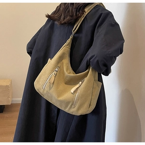 Detail of khaki canvas hobo bag showing retro crescent shape and multi-zipper pockets