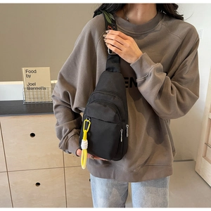Detail view of black nylon crossbody bag with floral strap and multiple zipper pockets