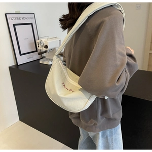 Vue détaillée du sac croissant en toile blanc cassé avec broderie rouge Dou Gu brodée