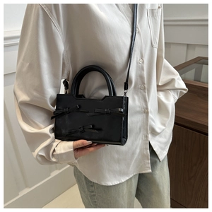 Detail of a black PU leather mini handbag featuring three elegant ribbon bows and dual handles