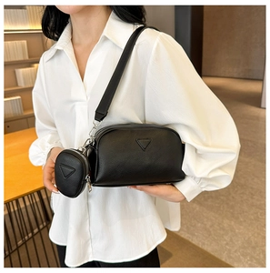Detail of black pebbled PU leather crossbody bag featuring a round coin purse and triangle patch
