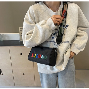 Détail du sac cylindrique noir en nylon avec broderie SJCHAO colorée et bandoulière à motifs