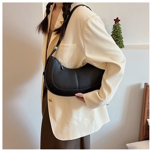 Detail of black pebbled leather crossbody bag showing crescent shape and silver hardware