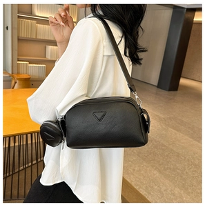Detail of black pebbled leather crossbody bag with a round mini coin purse and silver zipper