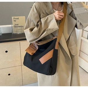 Chic black canvas crossbody bag with brown wide strap shown in minimalist Nordic setting