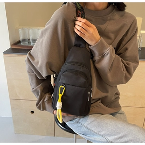 Close-up of black crossbody bag with colorful jacquard strap and yellow carabiner detail