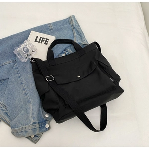 Fashionable black canvas tote bag with adjustable shoulder strap and metal snap pocket