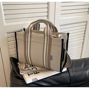 Minimalist canvas tote bag with striped straps and leather trim on a stylish couch